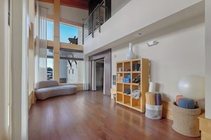 A spacious living area with a curved sofa, a wooden shelving unit, and a basket with exercise balls.