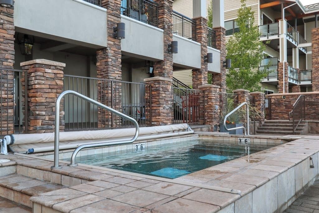 Zona de piscina con pilares de piedra, barandilla metálica y superficie de agua cristalina.