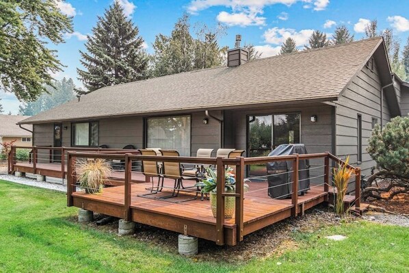 Ein modernes Haus mit Terrasse, Sitzgelegenheiten und Grillplatz.