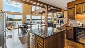 Een ruime keuken met een groot eiland, houten balken en uitzicht op een meer.