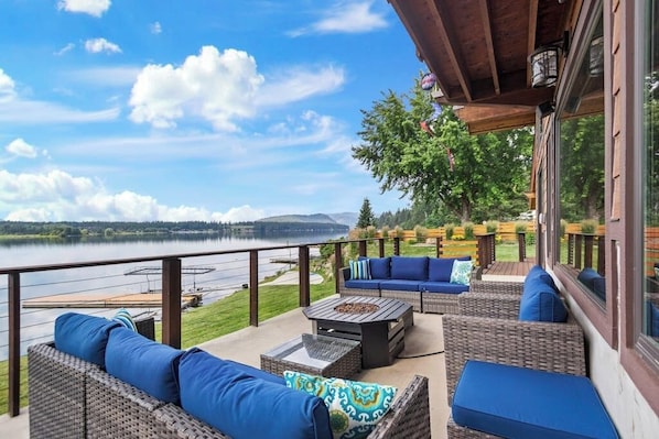 Eine überdachte Terrasse im Freien mit Korbmöbeln und Blick auf einen See.