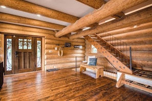 A log cabin interior with wooden walls, a wooden staircase, and a wooden floor.