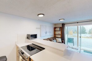 Eine moderne Küche mit eingebautem Herd, Mikrowelle und Backofen. Ein großes Fenster bietet Blick ins Freie.
