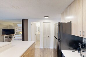 Eine moderne Küche mit Kühlschrank, Herd und einem Flachbildfernseher.