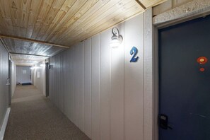 Ein Flur mit Holzboden, einem Schild mit der Nummer 2, einer Leuchte und einer Tür mit einem Telefon.