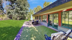 A modern building with a covered patio area, outdoor seating, and a well-maintained lawn.