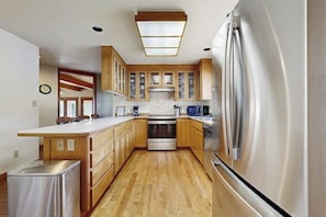 Eine Küche mit Holzausstattung, einem Edelstahlkühlschrank und einem eingebauten Backofen.