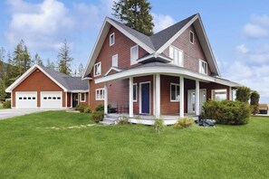 Ein zweistöckiges Haus mit Garage, überdachter Veranda und gepflegtem Rasen.