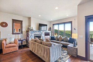 Ein Wohnzimmer mit Kamin aus Stein, einer Couch, einem Sessel und einem Fernseher.