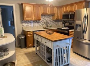 A modern kitchen with wooden cabinets, a stainless steel refrigerator, and a tiled backsplash. - 25 Sweet Serenity - Weiss Lake (Leesburg)