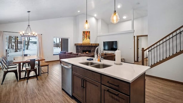 A modern kitchen with a central island, wooden cabinets, and pendant lighting.