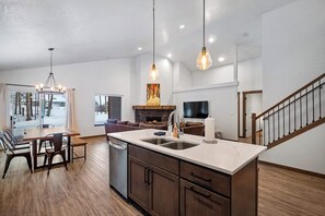 Une cuisine moderne dotée d’un îlot central, de meubles en bois et de luminaires suspendus.