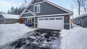 A two-story house with a garage, surrounded by snow.