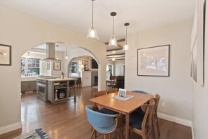 A modern kitchen with an island, pendant lighting, and a dining area with chairs and a table. - Centrally-Located Upscale House with Free WiFi, Porch & Oversized Fenced Yard (Sandpoint)