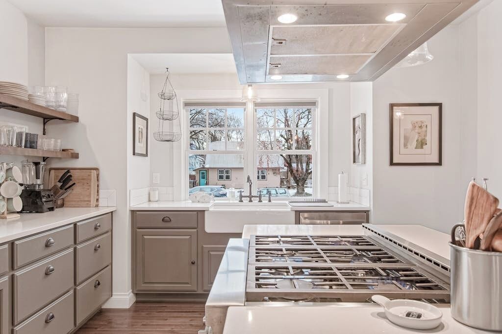 A modern kitchen with a central island, built-in appliances, and a large window providing a view of the outside.