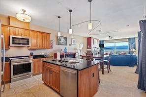 A modern kitchen with wooden cabinets, stainless steel appliances, and pendant lighting. - Lake view condo with WiFi, balcony, fireplace, & shared pool/hot tub/grills (Sandpoint)