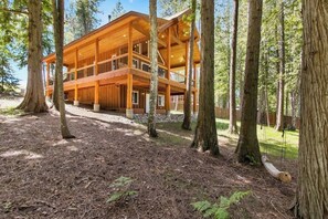 Eine mehrstöckige Holzhütte mit einer Terrasse, umgeben von Bäumen.