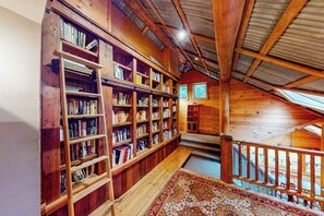 Un intérieur en bois avec des étagères, un escalier et une vue par la fenêtre.