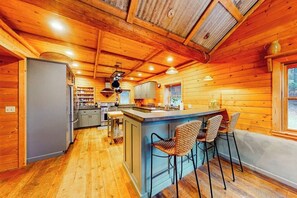 A wooden cabin interior with a kitchen, bar area, and seating.