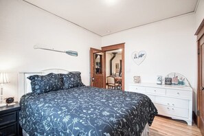 A bedroom with a bed, a dresser, a mirror, and a door leading to another room. - 2-story downtown home near the water with firepit, enclosed backyard, fireplace (Sandpoint)