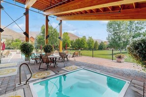 A pool area with a wooden pergola, lounge chairs, and a view of the surrounding landscape.