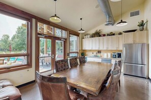 Une cuisine spacieuse avec une grande table à manger, des armoires en bois et un réfrigérateur en acier inoxydable.