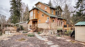 A two-story wooden house with a stone pathway leading to the front door. - Lakefront home with mtn views, private hot tub, dock, deck, & grill (Sandpoint)