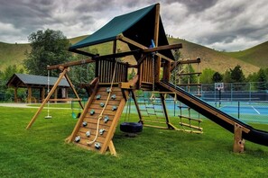 Une aire de jeux avec un toboggan, un mur d’escalade et des balançoires.