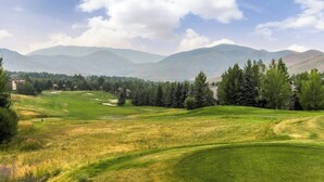 A golf course with rolling hills, trees, and distant mountains under a clear sky. - Mountain studio & loft with fireplace, near skiing & trails (Sun Valley)