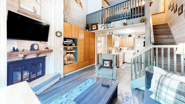 A spacious living area with a fireplace, a television, and a staircase leading to an upper level. - Mountain studio & loft with fireplace, near skiing & trails (Sun Valley)