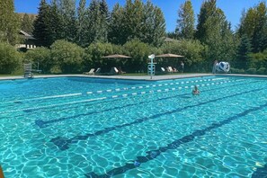 Une piscine avec des couloirs de nage, des chaises longues et des parasols.