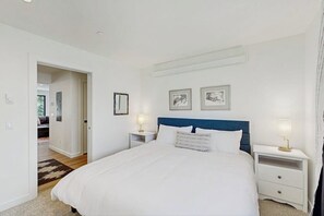 Ein Schlafzimmer mit einem großen Bett, zwei Nachttischen, einem Kopfteil und zwei gerahmten Bildern an der Wand.