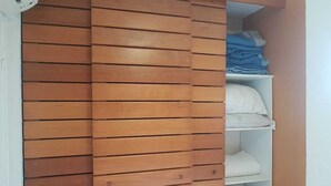 Ein Zimmer mit einem Schrank mit Schiebetüren aus Holz und einer weißen Regaleinrichtung mit gefalteter Kleidung.