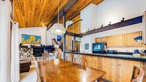 Un tavolo da pranzo in legno con sedie, una cucina con armadietti in legno, un muro in pietra e un dipinto di girasoli.