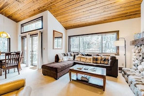 A cozy living room with a wooden ceiling, a sofa, a coffee table, and a fireplace. - Charming condo with mountain views, fireplace, hot tub & deck (Ketchum)