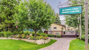 A pathway leading to a building labeled 'Olympic Pool Tennis Center,' surrounded by greenery and a well-maintained lawn. - Cozy Condo w/ Free WiFi, Heated Pool & Tennis - Close to Skiing (Sun Valley)