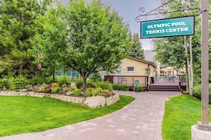 A pathway leading to a building labeled 'Olympic Pool Tennis Center,' surrounded by greenery and a well-maintained lawn. - Cozy Condo w/ Free WiFi, Heated Pool & Tennis - Close to Skiing (Sun Valley)