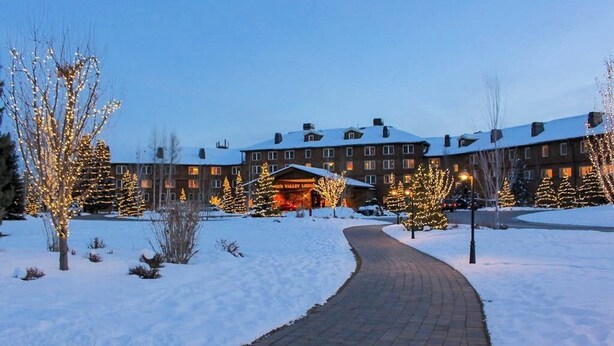 A snow-covered pathway leading to a building with multiple windows and a lit entrance. - Cozy Condo w/ Free WiFi, Heated Pool & Tennis - Close to Skiing (Sun Valley)