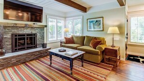 A living room with a stone fireplace, a sofa, a coffee table, and a rug.