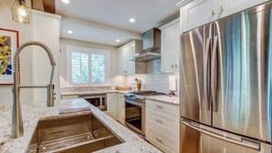 A modern kitchen with stainless steel appliances, a marble countertop, and a built-in oven.