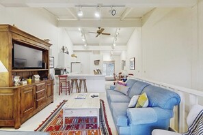 A spacious living area with a sofa, wooden cabinet, and a television. - Sunny Townhouse with WiFi, Views, Summer Pool, & Ski Bus Pick-Up (Sun Valley)