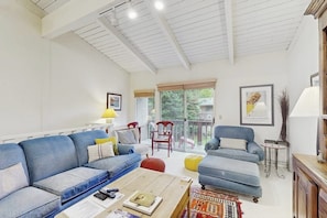 A living room with a blue sofa, a wooden coffee table, and a balcony with a view. - Sunny Townhouse with WiFi, Views, Summer Pool, & Ski Bus Pick-Up (Sun Valley)