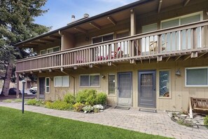 A two-story building with a balcony, multiple doors, and a small garden area. - Sunny Townhouse with WiFi, Views, Summer Pool, & Ski Bus Pick-Up (Sun Valley)