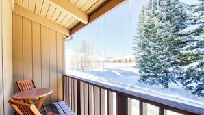 A wooden deck with a table and chairs, overlooking a snowy landscape with trees. - Cozy Mountain Abode with WiFi, Pool, & Perfect Location Near Downtown Ketchum (Sun Valley)