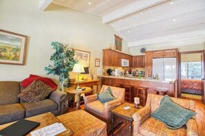 A cozy living room with a sofa, armchairs, a coffee table, and a dining area with a kitchen in the background. - Cozy Mountain Abode with WiFi, Pool, & Perfect Location Near Downtown Ketchum (Sun Valley)