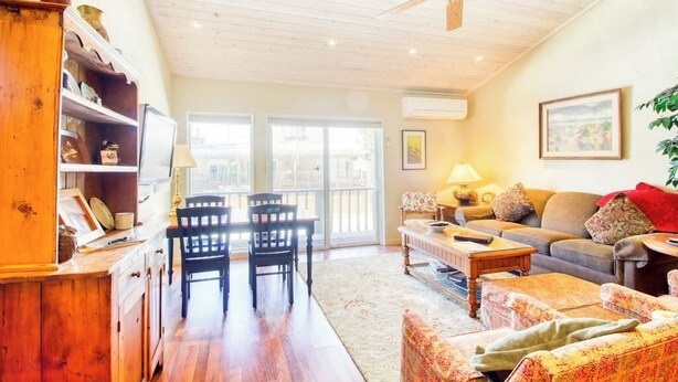 A spacious living room with a wooden ceiling, a dining area with chairs and a table, a sofa, and a large window with a view. - Cozy Mountain Abode with WiFi, Pool, & Perfect Location Near Downtown Ketchum (Sun Valley)