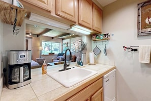 A kitchen with wooden cabinets, a coffee maker, a sink, and a dishwasher. - Cute Studio with Lots of Space, WiFi, Close to Skiing (Sun Valley)