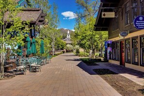 A paved walkway with outdoor seating, a church in the background, and a building with a sign for a restaurant reservation center. - Well-Located Condo w/ Access to Sun Valley Inn & Sun Valley Olympic Pools (Sun Valley)