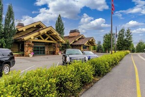 A lodge with a stone facade, a covered porch, and a parking area with cars. - Well-Located Condo w/ Access to Sun Valley Inn & Sun Valley Olympic Pools (Sun Valley)