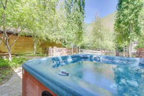 Ein Whirlpool in einem Garten mit Bäumen und einer Backsteinmauer.